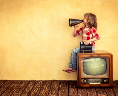 young girl sitting on television with megaphone